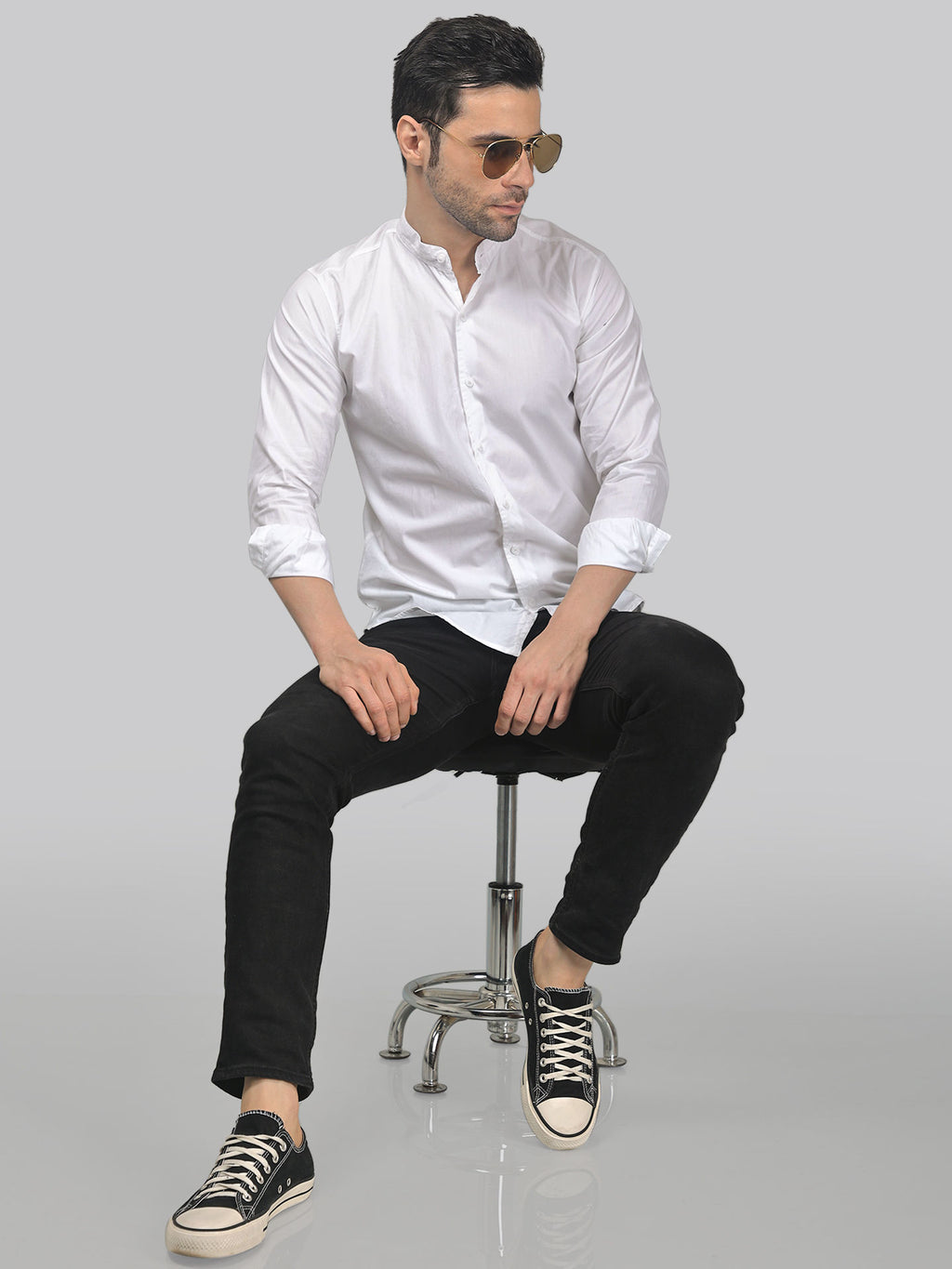 a man in a white shirt and black pants sitting on a chair