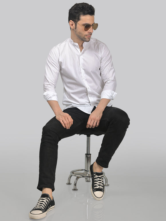 a man in a white shirt and black pants sitting on a chair