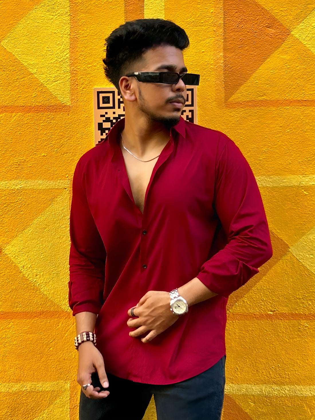 a man in a red shirt standing in front of a yellow wall