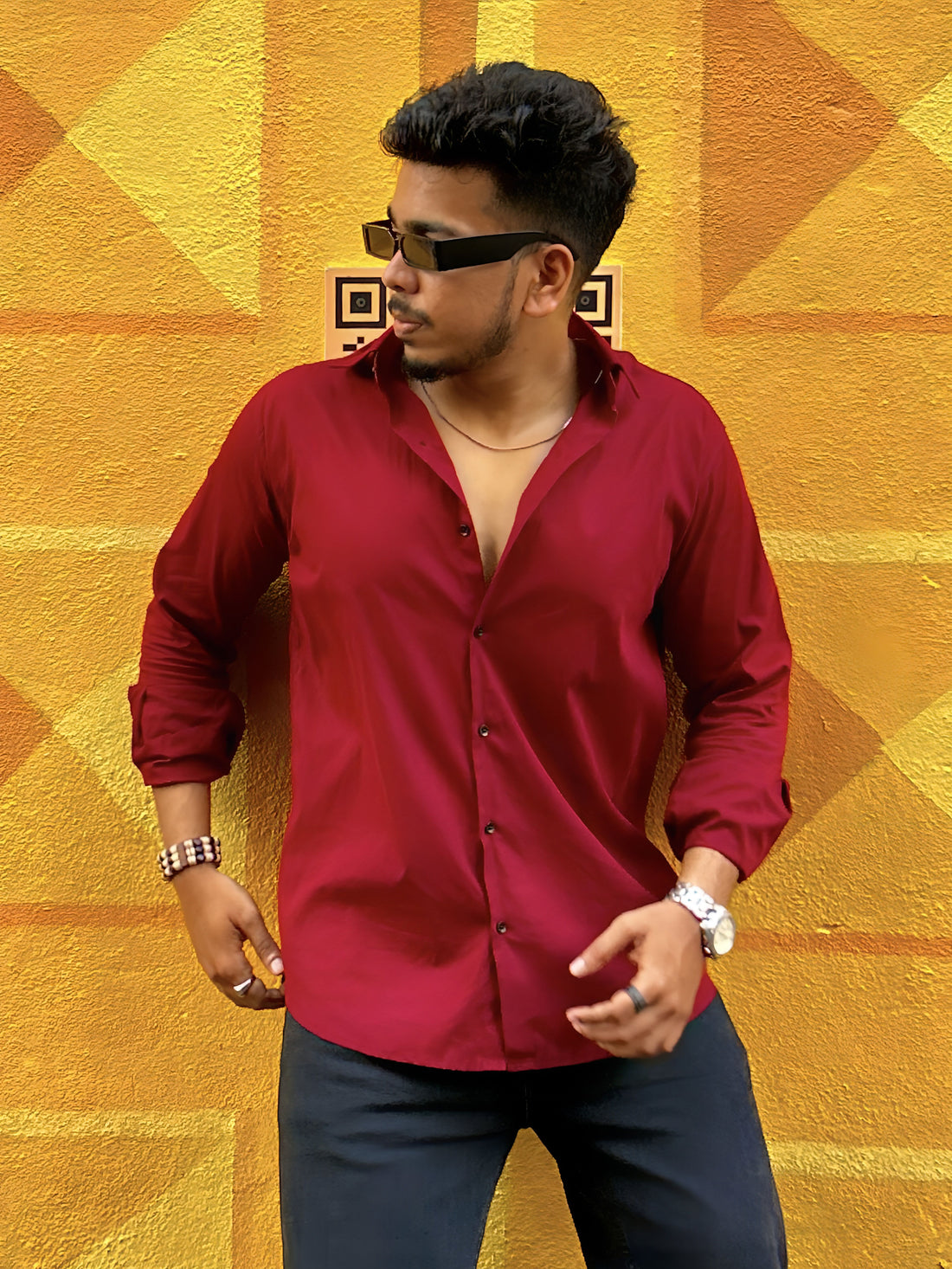 a man in a red shirt and sunglasses standing in front of a yellow wall