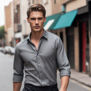 a man in a gray shirt and black pants walking down a street