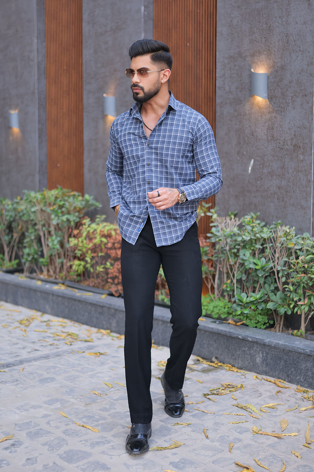 a man walking down a sidewalk wearing a blue shirt and black pants