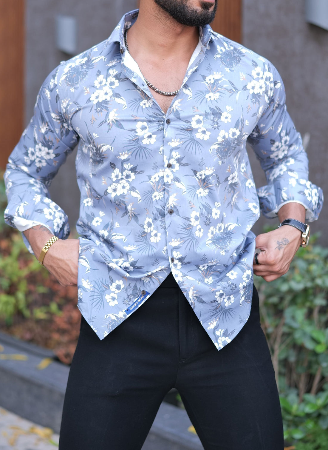 a man with a beard wearing a blue shirt and black pants