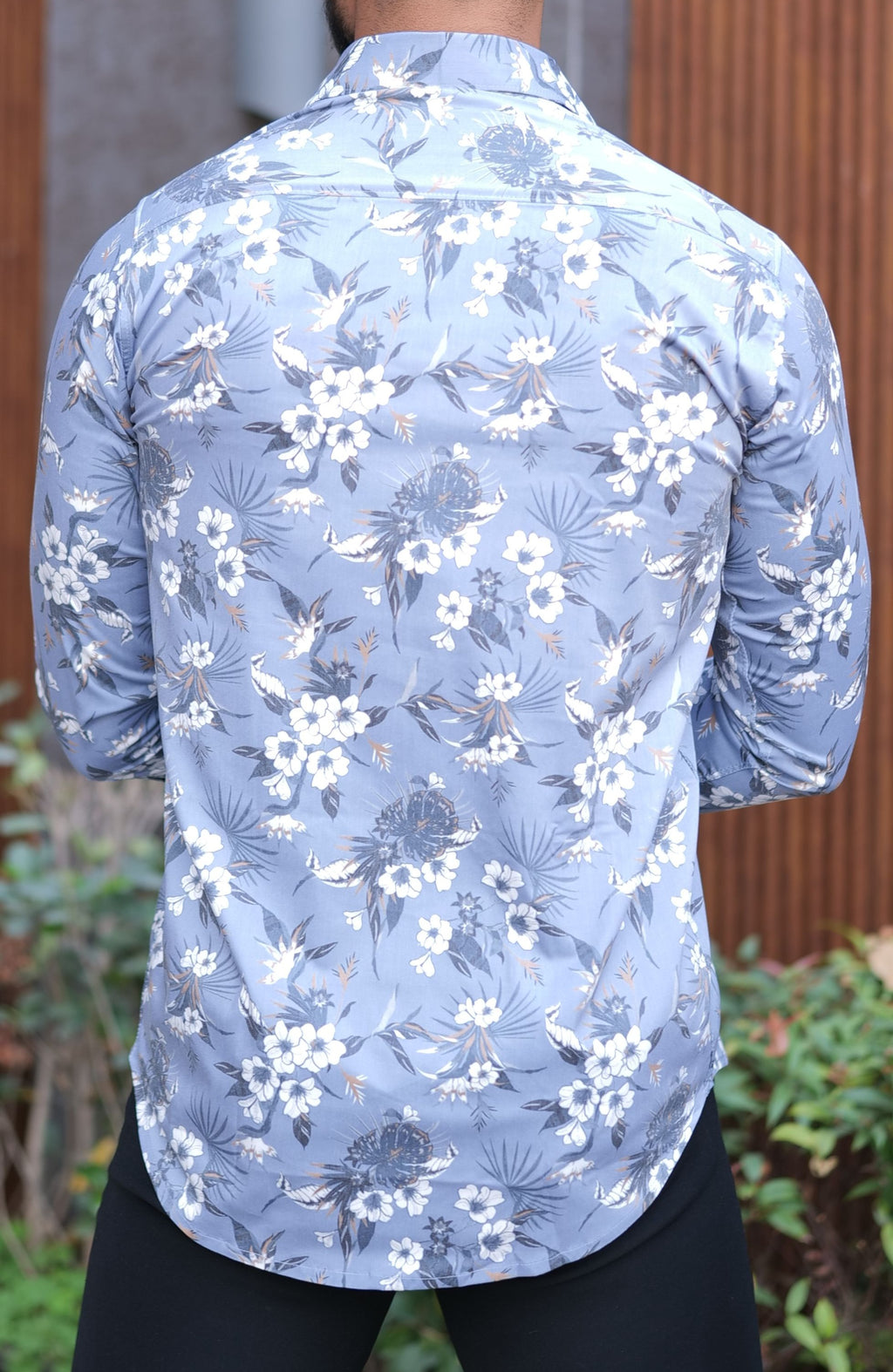 a man wearing a blue shirt with white flowers on it