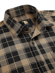 a brown and black plaid shirt with a black and white logo