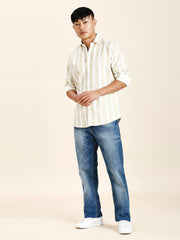 a man in a striped shirt and jeans poses for a picture