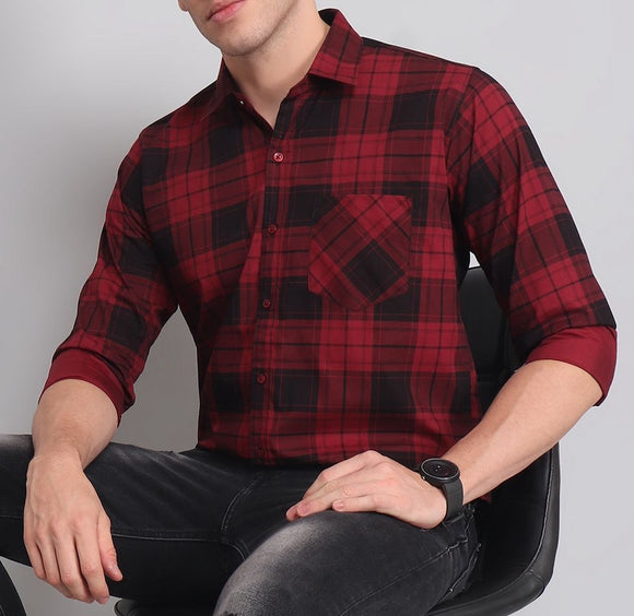 a man in a red and black shirt sitting on a chair