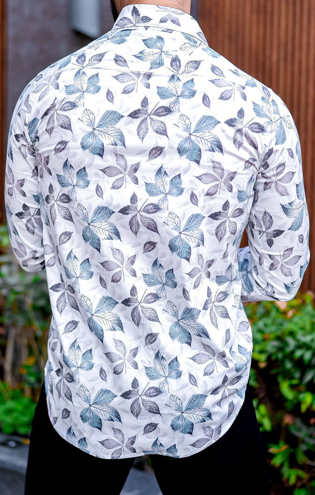 a man wearing a white shirt with blue leaves on it