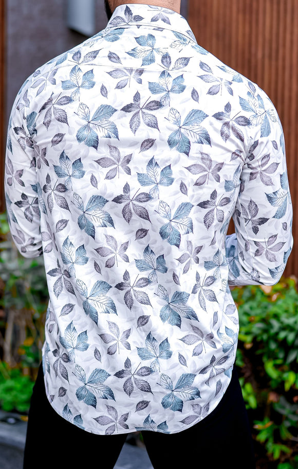 a man wearing a white shirt with blue leaves on it