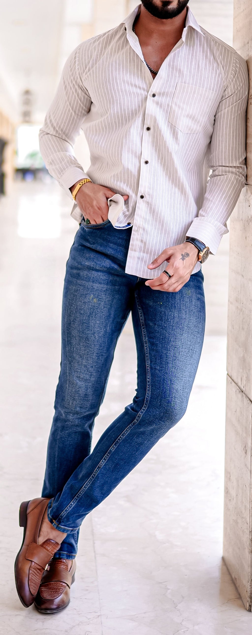 a man leaning against a wall with his hands in his pockets