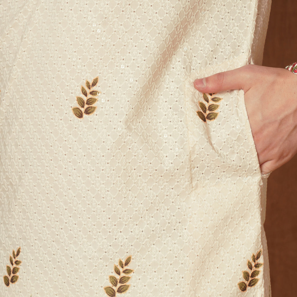 Close-up of cream Chikankari fabric with delicate embroidery and pocket detail. Features subtle harvest motifs for a refined ethnic look.