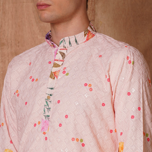Detailed neckline of pastel pink Chikankari kurta with floral inner placket. Traditional festive wear with subtle embroidery and vibrant accents.