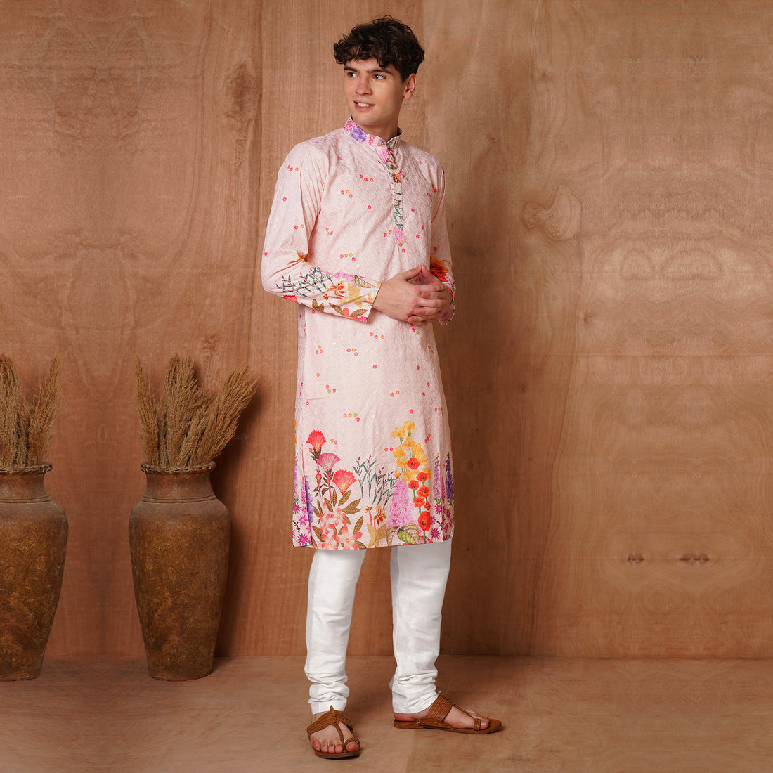 Angled front view of pastel pink floral kurta with Chikankari work. Styled for festive and wedding ethnic wear with colorful botanical prints.