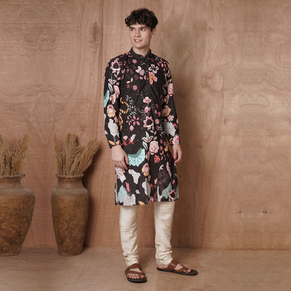 Men’s black kurta with tiger and floral print, styled for festive occasions like weddings and Diwali, paired with cream churidar pants.