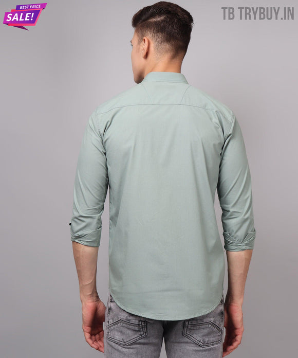 a man wearing a light green shirt and jeans