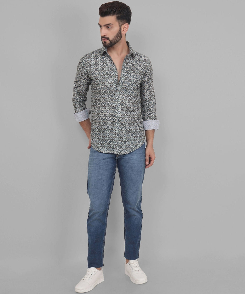 a man wearing a shirt and jeans standing in front of a gray background